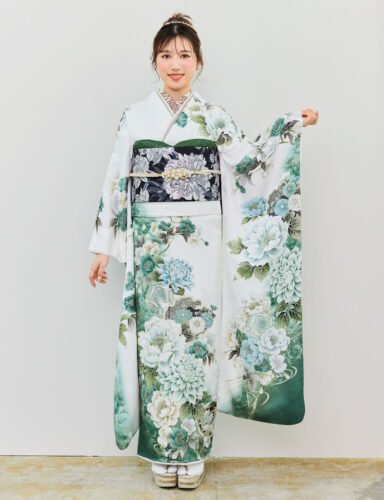 白地の振袖に緑・青・水色の花柄をあしらい、黒地の帯を合わせた女性が、爽やかで上品な振袖姿を見せている様子。