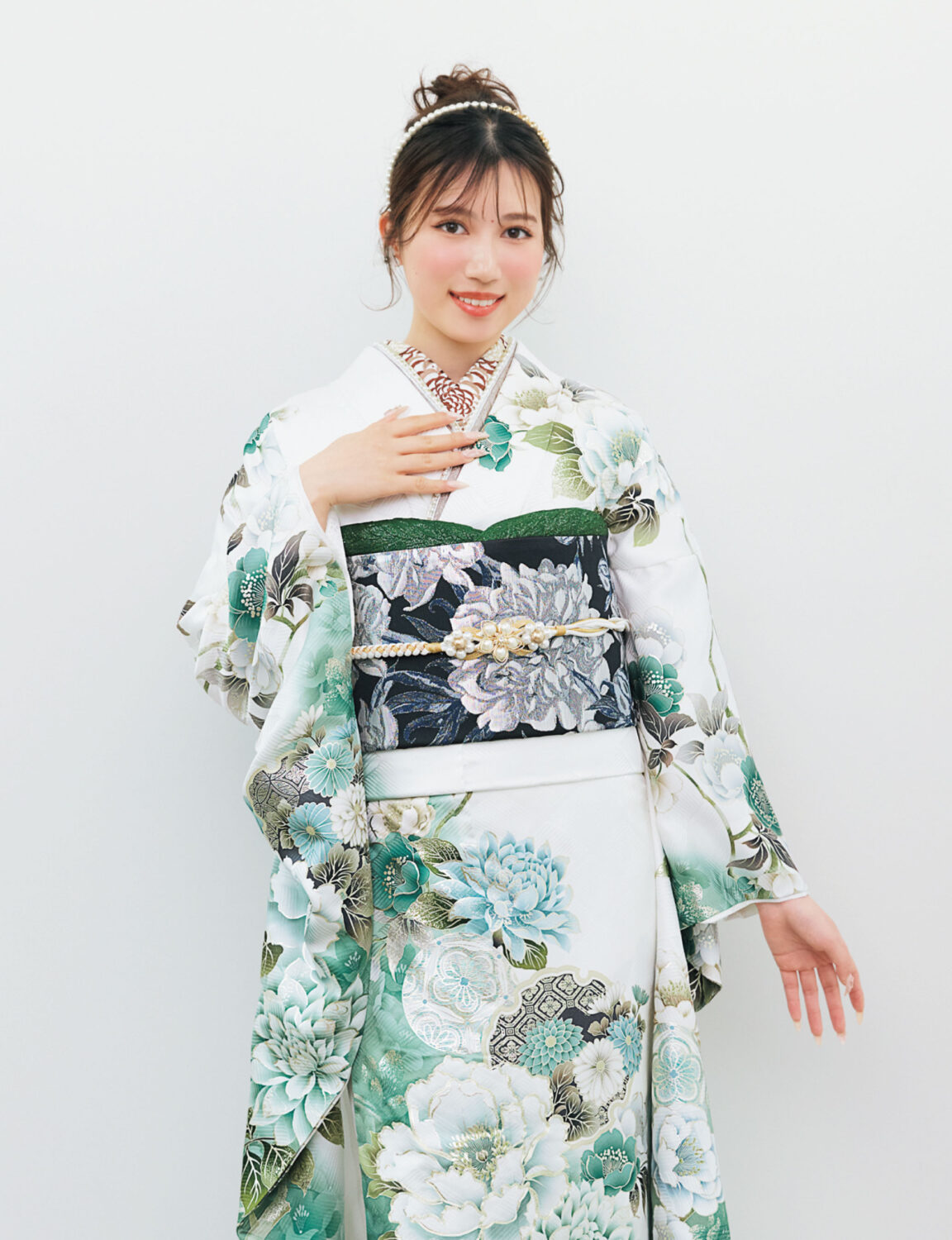 白地の振袖に緑・青・水色の花柄をあしらい、黒地の帯を合わせた女性が、爽やかで上品な振袖姿を見せている様子。