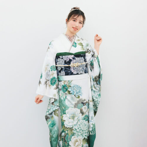 白地の振袖に緑・青・水色の花柄をあしらい、黒地の帯を合わせた女性が、爽やかで上品な振袖姿を見せている様子。