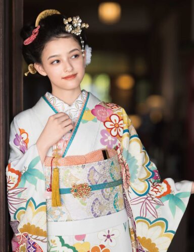 品の良さを醸し出す胡粉色の晴れ着は、華やかな色調の吉祥文様が好印象。表情豊かなちりめんの生地に、手描き友禅ならではの風雅が宿ります。