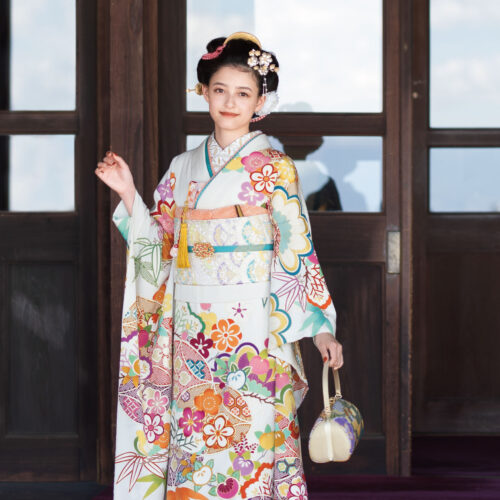 品の良さを醸し出す胡粉色の晴れ着は、華やかな色調の吉祥文様が好印象。表情豊かなちりめんの生地に、手描き友禅ならではの風雅が宿ります。