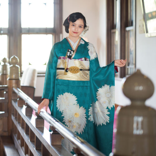 個性が際立つターコイズの着物を、大胆な余白で魅せる心憎い意匠。純白の万寿菊に惜しみなく金刺繍を施し、記念すべき日に華を添えます。