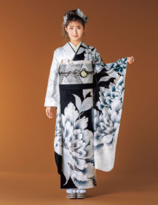 黒と白の振袖に大輪の花模様をあしらい、幾何文様の帯と白の帯締を合わせた女性の立ち姿
