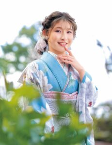 水色の振袖に白牡丹と淡い花々をあしらい、銀灰色の帯と帯締を合わせた女性の立ち姿